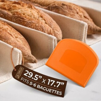Baguettes in a baking tray with an orange dough scraper.