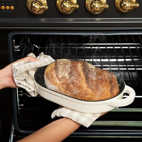 Person taking freshly baked bread out of the oven.