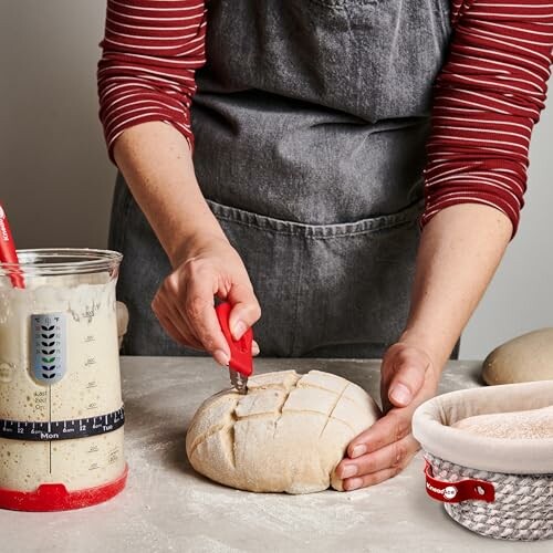 Person scoring bread dough with a tool.